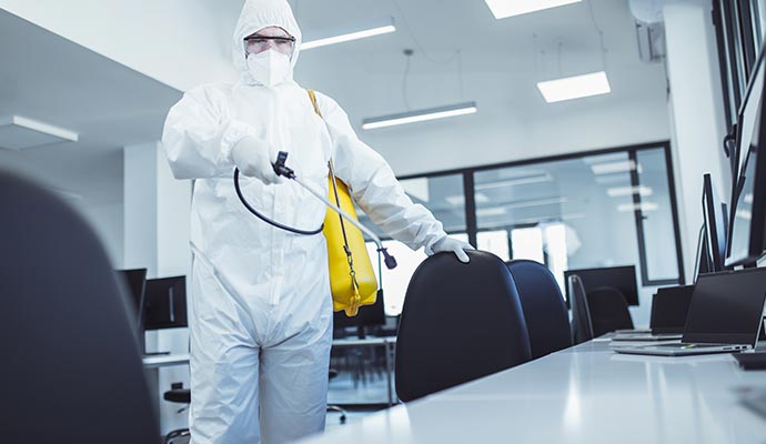 office disinfection man in protective suit and spraying for disinfection